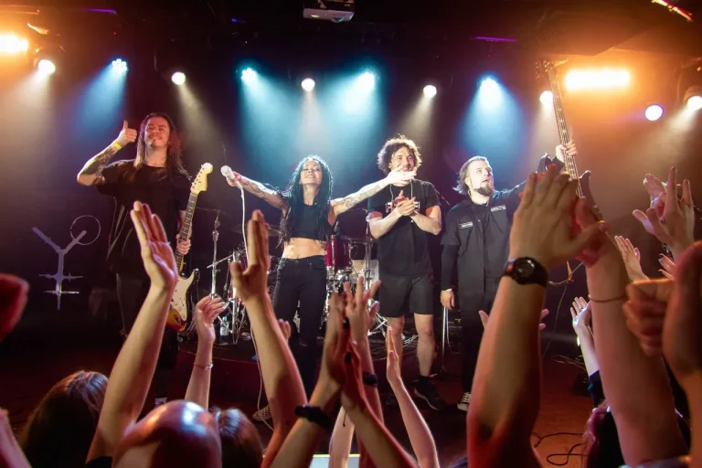 Nuki on a club stage, the audience in front of them with raised hands