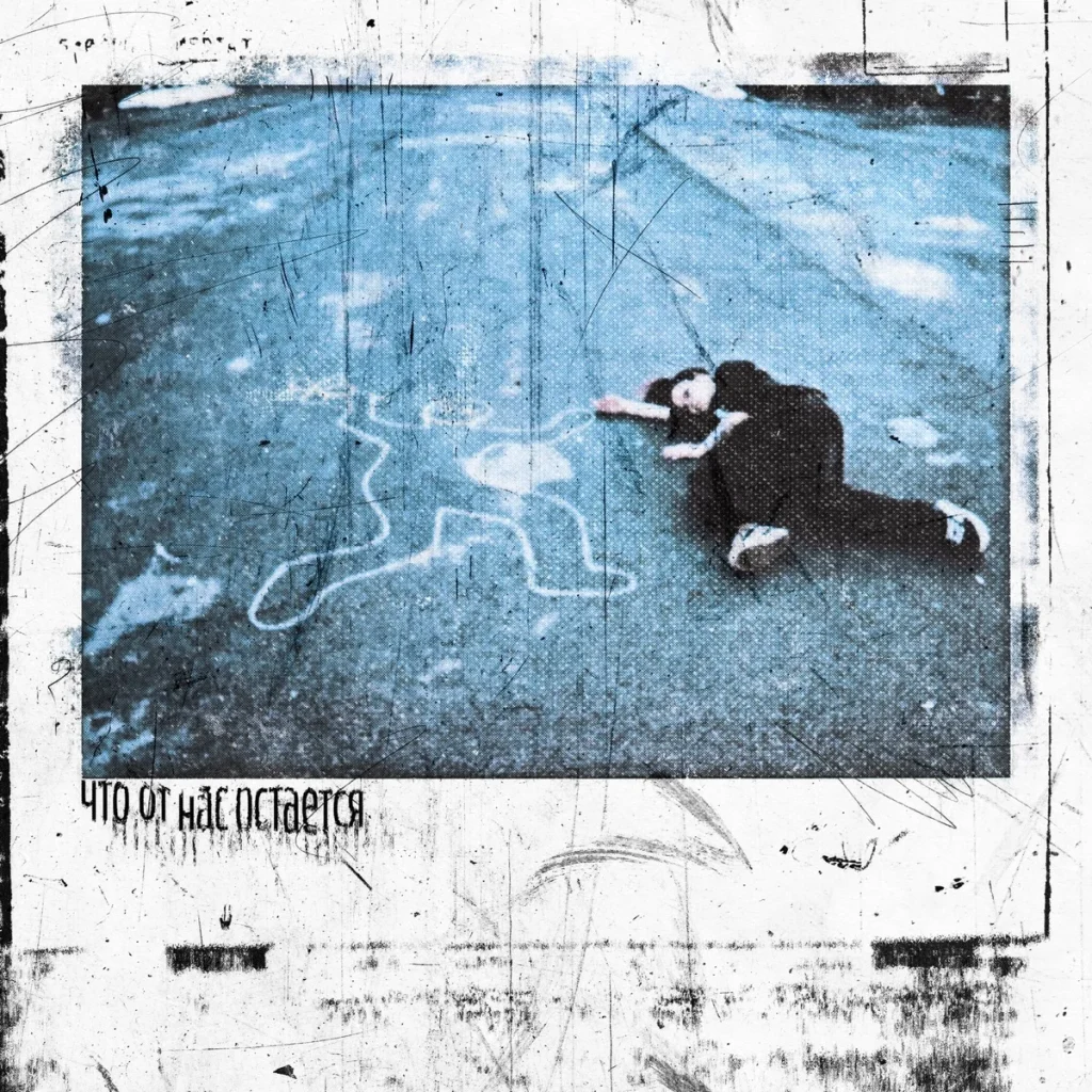 A person lying on asphalt next to a chalk body outline, with the words “Chto ot nas ostayotsya”