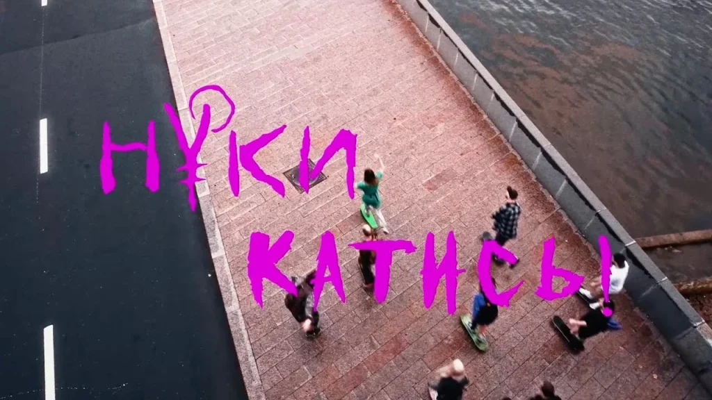 Skateboarders on an embankment seen from above, with the words “Nuki Katis!”